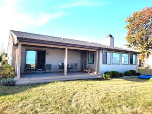 a house with a deck with chairs and a table at New! Huron Paradise - Family-friendly Lakefront! in Au Gres