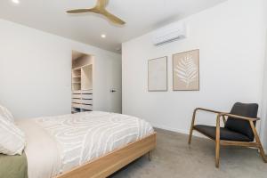 a bedroom with a bed and a chair at Sandy Soles in Agnes Water +31 photos