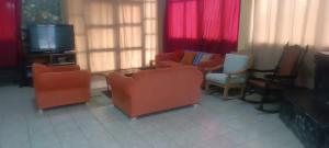 a living room with orange chairs and a flat screen tv at Cozy Rural House in Apata - Jauja 