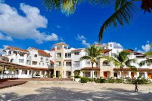 a large white building with palm trees in front of it at Cadaques Bayahibe Family Apts in Bayahibe