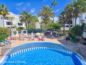 una piscina en un complejo turístico con palmeras en Sunwhere Colon II apartment - Playa De Las Américas, en Arona