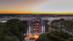 a building on a hill with the sunset in the background at Flat 102 Conforto e Charme in Canela