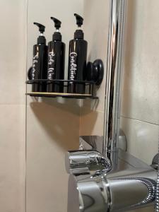 ティラナにあるVibe Comfort Tiranaのシンクの上の棚に並んだ黒いボトル +6枚の写真