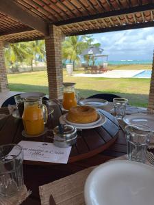a wooden table with food and orange juice on it at MHV Milagres - Casa Mar, Refugio a beira mar na Paradisíaca praia da enseada do toque in São Miguel dos Milagres