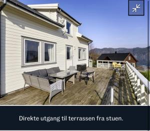 a deck with a table and chairs on a house at Feriehus Tripperåsen Moi in Eikje