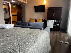 a hotel room with a bed and a couch and a tv at Quarto de hotel na Rua Verbo Divino in Sao Paulo