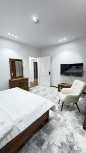 a bedroom with a bed and a chair and a television at ملاذ العلا in AlUla