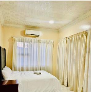 Un dormitorio con una cama blanca y una ventana. en Grand Tranquil Views, en Lobamba