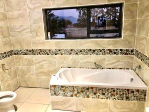 baño con bañera, ventana y aseo en Grand Tranquil Views, en Lobamba 16 fotos más