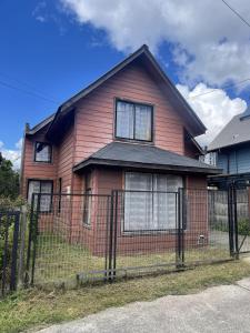 a pink house with a fence in front of it at Casa Rukalma Estación in Villarrica