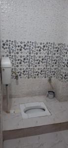 een badkamer met een toilet en een witte muur bij Raghuvar Vilas in Varanasi