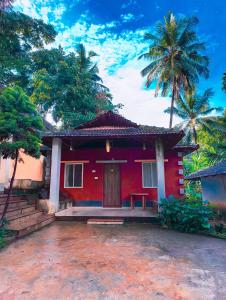 une maison rouge avec des palmiers en arrière-plan dans l'établissement Kamath regency and cottages marriage Hall, à Dharmastala