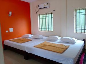 - une chambre dotée d'un lit avec des draps blancs et des murs orange dans l'établissement Kamath regency and cottages marriage Hall, à Dharmastala