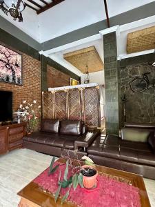 a living room with a leather couch and a table at Mangir Homestay in Banyuwangi