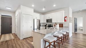 una cucina con armadi bianchi e un'isola con sgabelli da bar di Cozy Swiss Condo -King Bed, Sleeps 6, Free Blanket a Midway