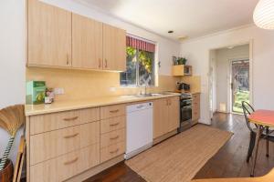 a kitchen with wooden cabinets and a table and chairs at Pippis a Classic Beach House in Seal Rocks