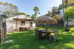 a table with chairs and an umbrella in a yard at Pippis a Classic Beach House in Seal Rocks