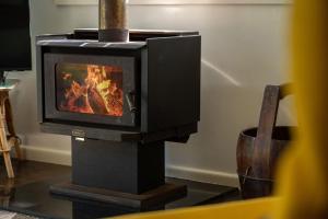a wood stove with a fire in a room at Pippis a Classic Beach House in Seal Rocks