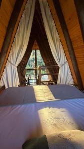 a large bed in a tent with a window at Vistas de Mantiqueira in Bom Jardim da Serra