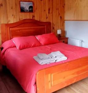 Una cama con almohadas rojas y dos toallas encima. en Lara cabañas, en Guaymallén