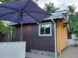 a purple umbrella in front of a small house at Bungalow Dumonter in Baie-Mahault