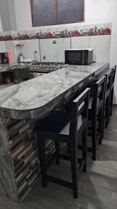a kitchen with a marble counter top and chairs at Casa Alexita in Puerto Baquerizo Moreno