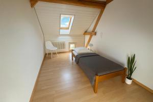 a attic room with a bed and a chair at Aussergewöhnliche Loft Wohnung mit Hängenetzen und Schaukeln in Frauenfeld