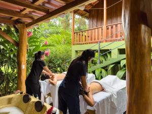 two womenitioning a man on beds on a porch at Hotel Rancho Cerro Azul in Fortuna