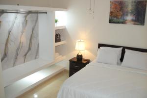 a bedroom with a bed and a lamp on a night stand at Luxury GuestHouse Suites in Cap-Haïtien