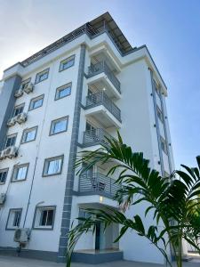 a white building with balconies and palm trees at Luxury GuestHouse Suites in Cap-Haïtien