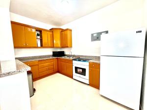 a kitchen with wooden cabinets and a white refrigerator at Luxury GuestHouse Suites in Cap-Haïtien +4 photos