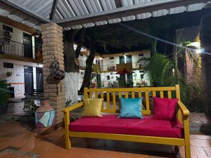 een gele bank met kleurrijke kussens op een terras bij Hotel La Casona Valledupar in Valledupar