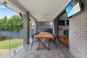 a patio with a wooden table and chairs at Bright Family Home in Rydalmere with Yard & BBQ in Sydney