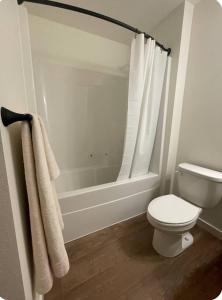 a white bathroom with a toilet and a bath tub at Home at Kingwood in Forest Grove in Forest Grove