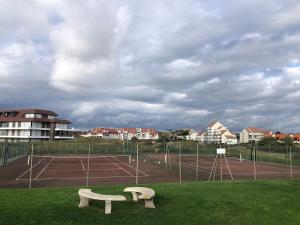 a tennis court with two benches on a tennis court at Studio vue sur la mer in Neufchâtel-Hardelot