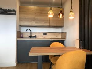 a kitchen with a wooden table and yellow chairs at Studio vue sur la mer in Neufchâtel-Hardelot +9 photos