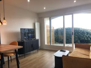 a living room with a couch and a tv and a table at Studio vue sur la mer in Neufchâtel-Hardelot