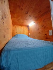 een slaapkamer met een blauw bed in een houten kamer bij El Balcón de la Tata Hostel in San Salvador de Jujuy