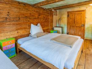 a bed in a room with a wooden wall at Alte Grafenmühle in Hopfgarten im Brixental