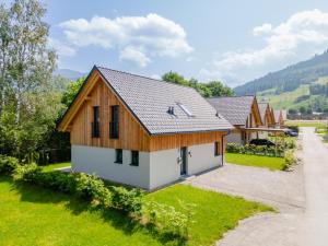 a house with a wooden roof and a green yard at Mountain Chalet Alpinchique 2 in Sankt Lorenzen ob Murau
