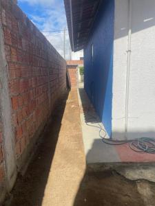 a brick wall next to a sidewalk next to a building at Casa aconchegante in Garanhuns