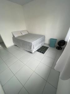a bed sitting on a white tiled floor in a room at Casa aconchegante in Garanhuns