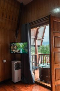 a living room with a flat screen tv and a window at Pondanu Living in Bedugul