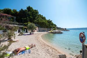 a man laying on a beach next to the water at Apartments with parking space Sumpetar, Omis - 951 in Sumpetar +12 photos