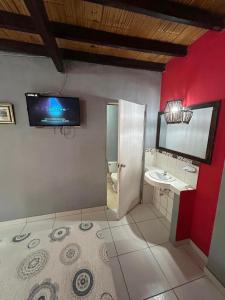 ein Badezimmer mit Waschbecken und einem Fernseher an der Wand in der Unterkunft La casa de Jessi in Máncora