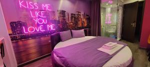 a purple bedroom with a bed with a sign that reads kiss me like you love at Boutique Hotel in Hanoi