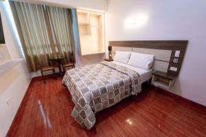um quarto com uma cama, uma mesa e uma janela em Hotel INTI TUMI em Lima