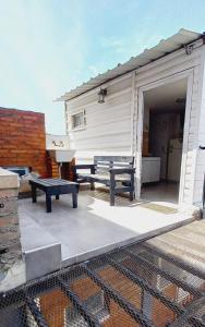 eine Terrasse mit zwei Picknicktischen und einem Gebäude in der Unterkunft Jeleta 1 in Puerto Madryn