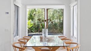 a dining room with a glass table with chairs and a window at 2 Marma Retreat - Peaceful Surrounds with Heated Pool & Spa in Red Hill