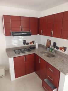 a kitchen with red cabinets and a sink at Apartamento familiar, tranquilo in Curití